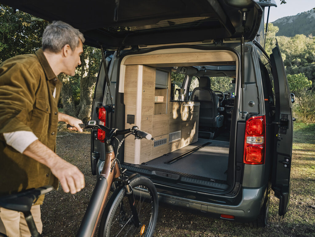 un homme charge un vélo dans un van aménagé spacetourer holidays