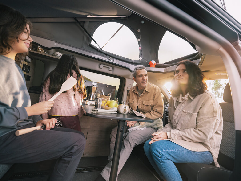 une famille déjeune à l'intérieur d'un van aménagé spacetourer holidays